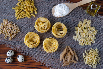Different types of pasta on a wooden table on a tissue napkin.