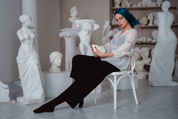 Beautiful young girl with blue hair in the sculptor's studio.