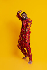 Funny handsome guy in african dress posing over yellow