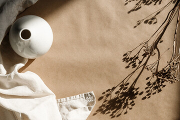 Minimalist kraft paper  background with a ceramic vase and dry grass.