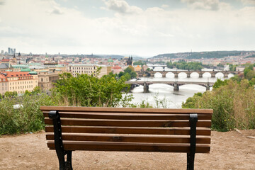 Empty bench at a beautiful vista point in Letna, Prague with a blurred view of the many bridges of Prague and parts of the town
