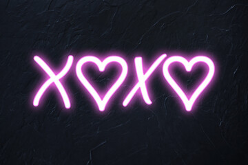 xoxo written in pink neon style with hearts on black wall background