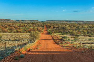 Dirt road to Chambers Pillar in the Northern Territory of Australia with trees and shrubs on both...
