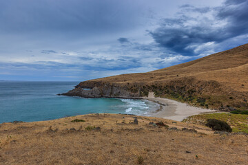 Landscape of Blow hole Beach in the Deep Creek Conservation Park, Fleurieu Peninsula, South Australia overlooking the beach, the sea and deeply cut mountain slopes with grass and trees