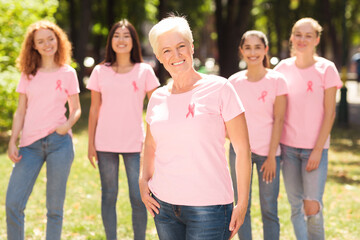 Cheerful Woman Standing With Breast Cancer Support Group In Park