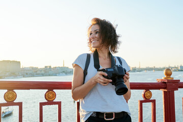 Mature female photographer with professional camera and backpack