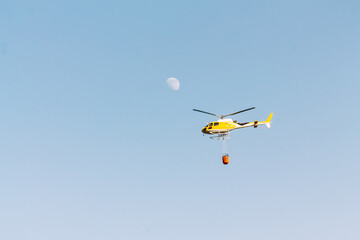 Helicopter flying with sky and moon background. Firefighter concept and extinguishing fires and wildfires.