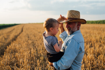man holding his grandson standing in wheat field