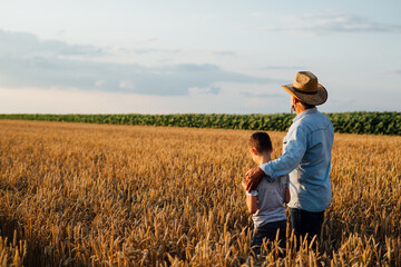 man holding his grandson standing in wheat field