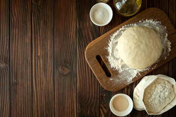 Baking in rural kitchen. Dough and recipe ingredients on vintage brown wooden table. Top view. Rustic background