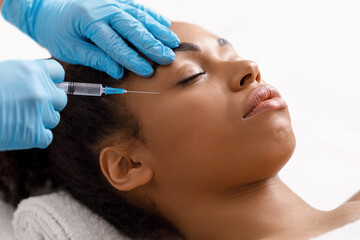 Black woman getting eye injection at salon