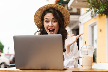 Portrait of surprised woman making video call on laptop in cafe