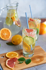 Health care, fitness, healthy nutrition diet concept. Fresh cool homemade citrus infused detox water with grapefruit, orange, lemon and lime and ice in a jug and glasses for spring summer days.