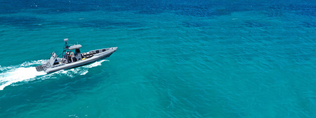 Naklejka premium Aerial drone ultra wide photo of rigid inflatable speed boat cruising in deep blue Aegean sea, Greece