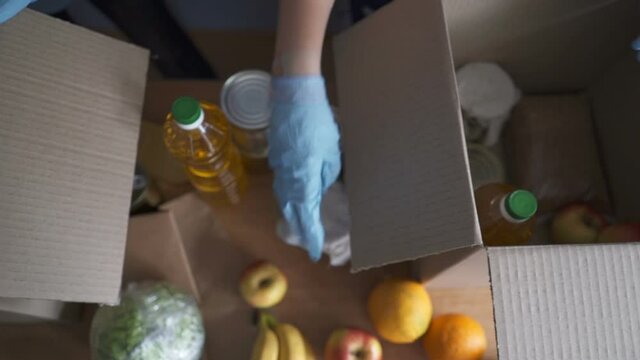 Volunteer in protective suits pack products. Food delivery services during coronavirus pandemic for working from home and social distancing. Shopping online.