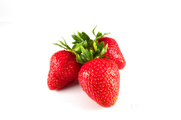 Three ripe red strawberries with green leaves on a white background. Isolated.