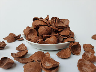 Cocoa crunch cereal or cornflakes, on a small plate. Isolated in white background.