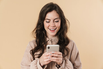 Image of cheerful cute woman smiling and typing on mobile phone