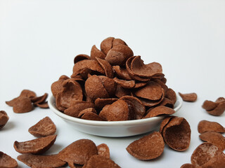 Cocoa crunch cereal or cornflakes, on a small plate. Isolated in white background.