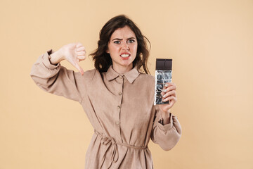 Image of displeased woman showing thumb down and holding chocolate