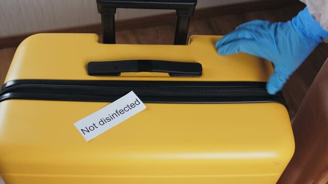 Close-up of women's hands disinfecting the surface of the suitcase. Opening borders after the end of the quarantine. Precautionary measures.