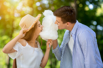 Lovely girl with her boyfriend eating cotton candy together at park