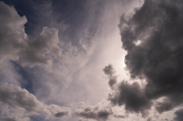 a background of gray atmospheric clouds and a cloud in the shape of a demonic head looking down