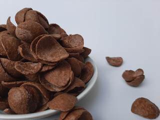 Cocoa crunch cereal or cornflakes, on a small plate. Isolated in white background.