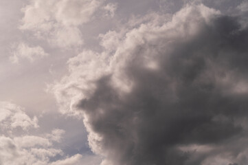 background of gray atmospheric clouds and clouds in the shape of a human face looking at the sunlight