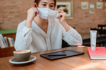 New normal with face mask and hand gel. Asian woman lifestyle alone. Working online out of office.