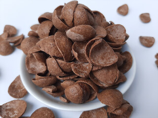 Cocoa crunch cereal or cornflakes, on a small plate. Isolated in white background.