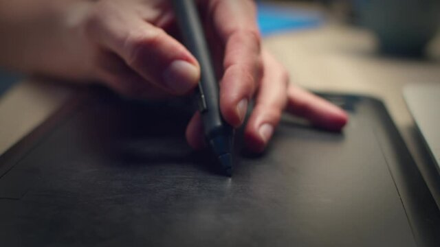 Male hands draw with pen on tablet at home at night.