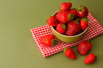 Fresh red strawberries in a bowl on green background and towel