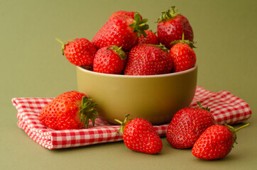 Fresh red strawberries in a bowl on green background and towel