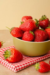 Fresh red strawberries in a bowl on wood table  background and towel