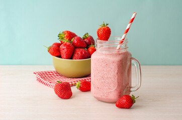 Strawberry smoothie or milkshake in mason jar on 
light wood table. Healthy food for breakfast and snack.