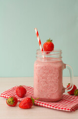 Strawberry smoothie or milkshake in mason jar on 
light wood table. Healthy food for breakfast and snack.