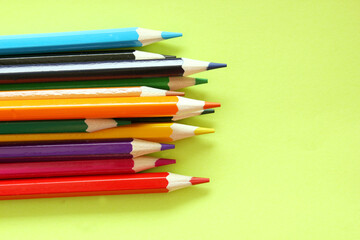 Colored pencils on a yellow background. Lots of different colored pencils. Colored pencil. Pencils are sharp. Pencils are on the left. Close-up. Copy space. Background. Flat lay.