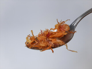 Heap of fried onion crisp in a metal spoon. Isolated in white background.