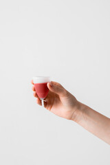 Menstrual cup eco friendly reusable and silicone in woman's hand with menstrual fluid isolated on a white background