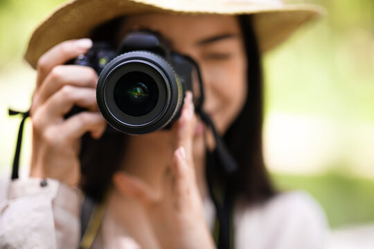 Young asian girl taking photos in the park with modern camera, closeup