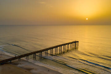 Fototapeta na wymiar A hazy sunrise from Saharan Dust in the atmosphere at the Saint Augustine Beach pier in Florida.