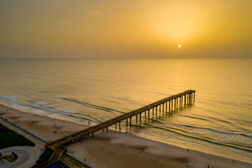 Obraz premium A hazy sunrise from Saharan dust in the atmosphere at the Saint Augustine Beach pier in Florida.