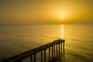 Fototapeta premium A hazy sunrise from Saharan dust in the atmosphere at the Saint Augustine Beach pier in Florida.