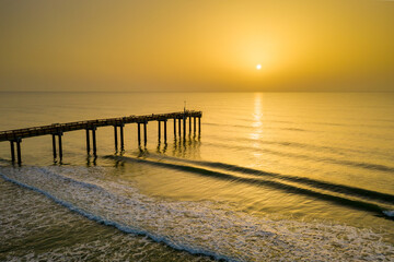 Fototapeta na wymiar A hazy sunrise from Saharan dust in the atmosphere at the Saint Augustine Beach pier in Florida.