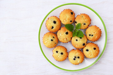 Delicious homemade vanilla muffins with raisins and pieces of white chocolate, decorated with melissa leaves