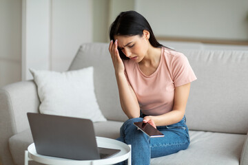 Sad Girl At Laptop Holding Cellphone Sitting On Couch Indoor