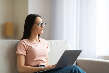 Woman Working On Laptop Thinking Sitting On Couch At Home