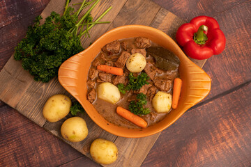 Beef goulash stewed with potatoes, carrots, and spices in a ceramic pot