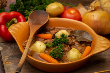 Beef goulash stewed with potatoes, carrots, and spices in a ceramic pot